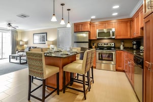 Una cocina moderna con armarios de madera, electrodomésticos de acero inoxidable y una isla central con taburetes de bar.