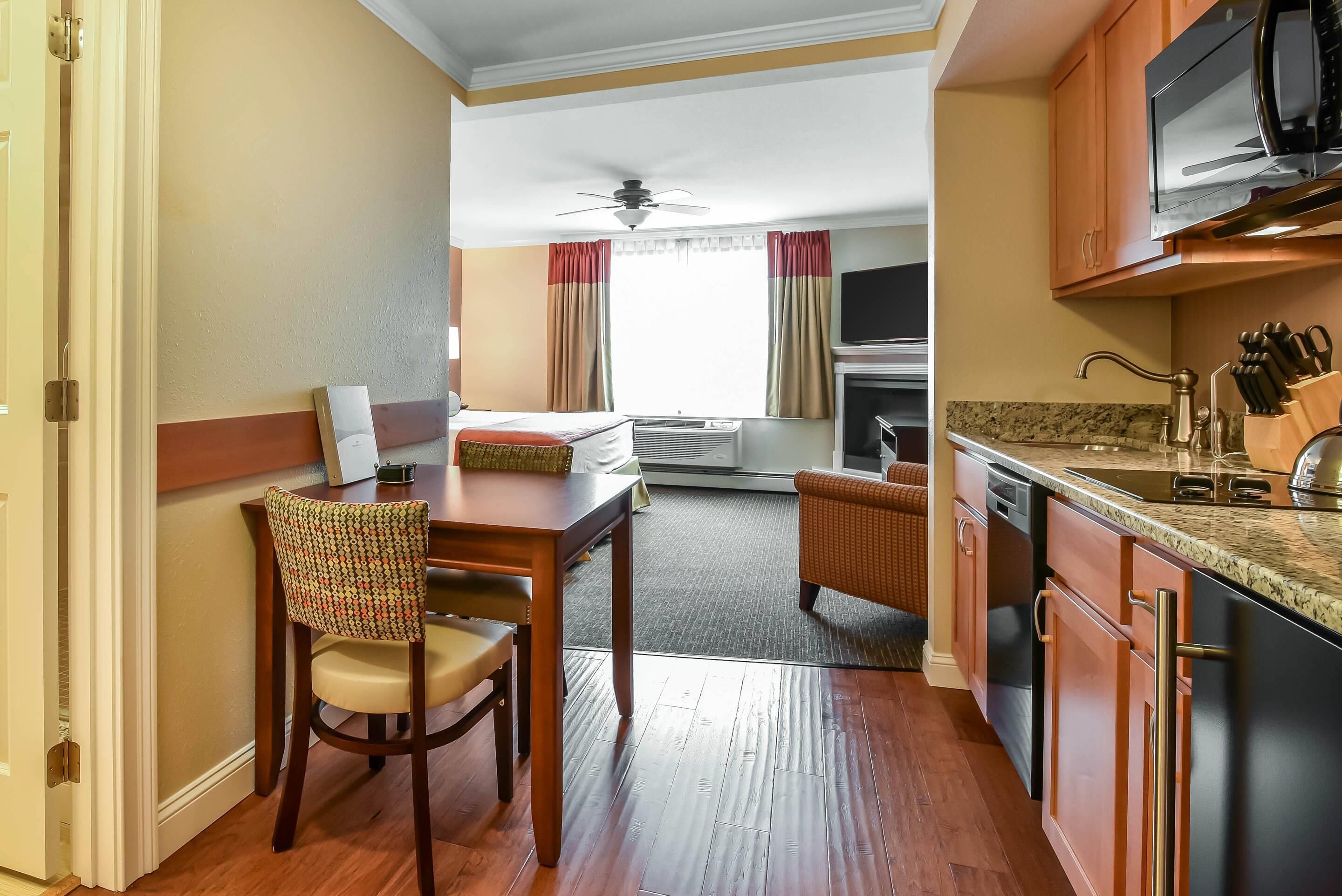 Habitación de hotel compacta con zona de comedor, kitchenette y cama.