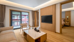 Un salon moderne avec un téléviseur à écran plat, un canapé, une table basse et un plancher en bois.