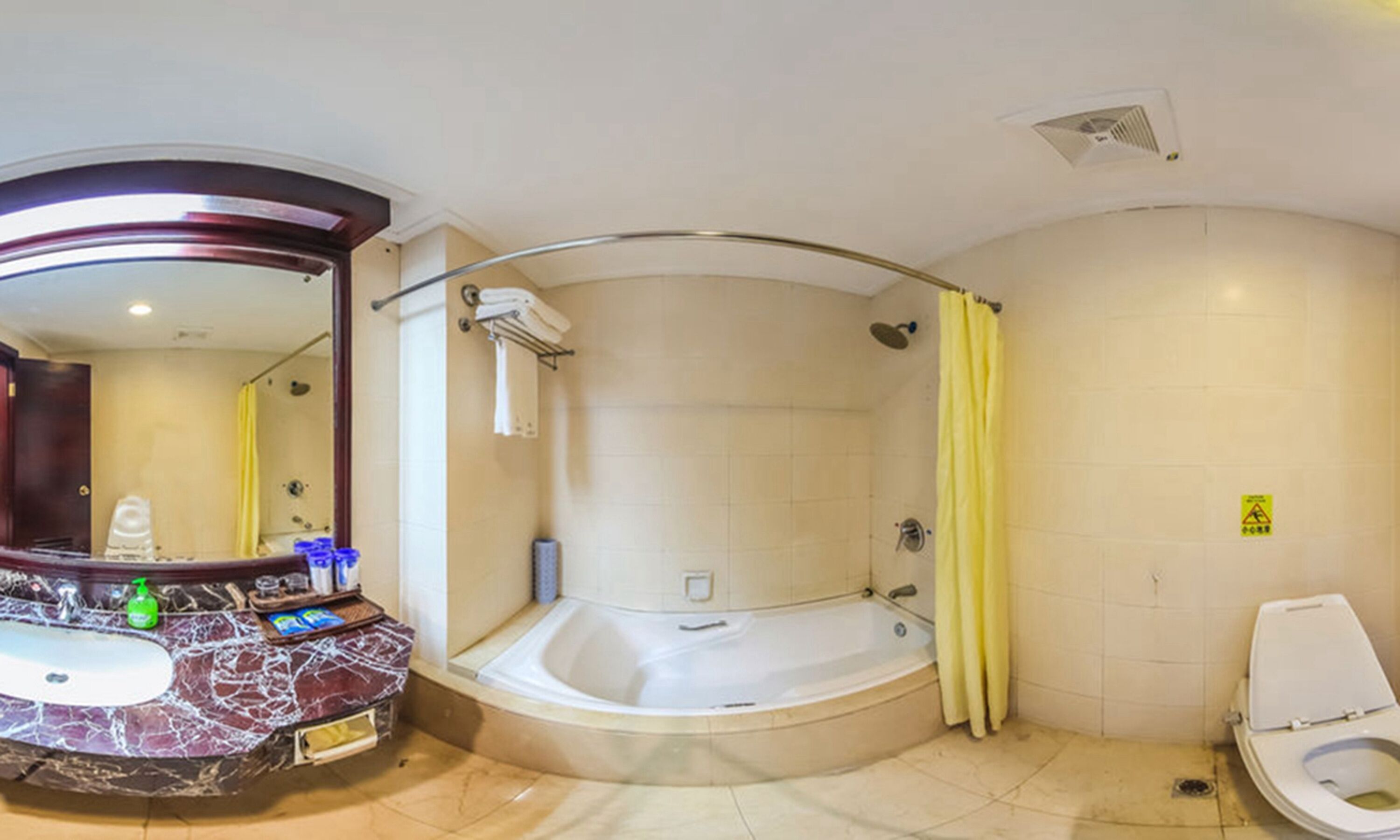 A bathroom with a marble sink, a bathtub, a toilet, and a shower with a yellow curtain.