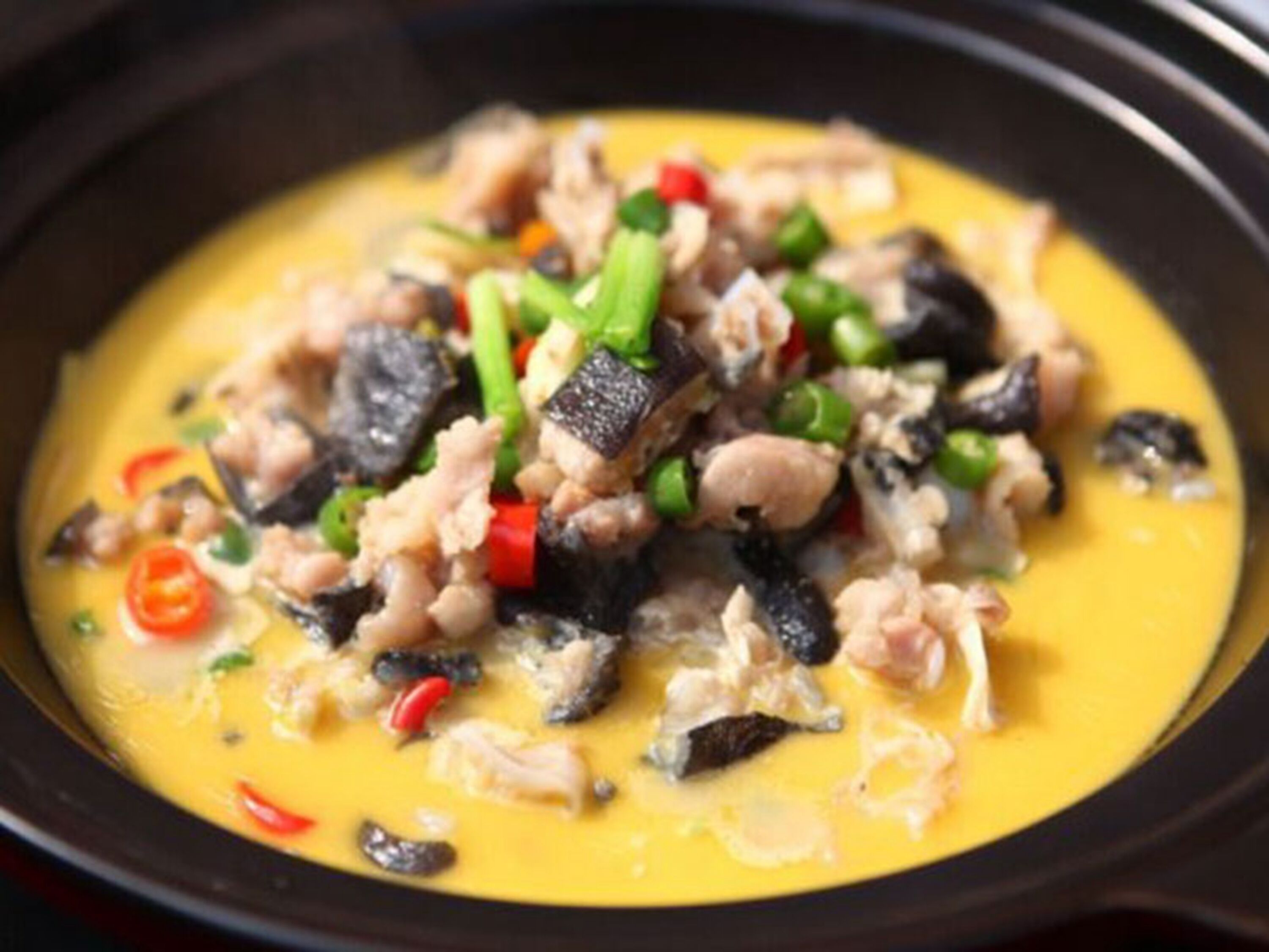 A dish with various ingredients in a yellow sauce.
