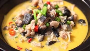 A dish with various ingredients in a yellow sauce.