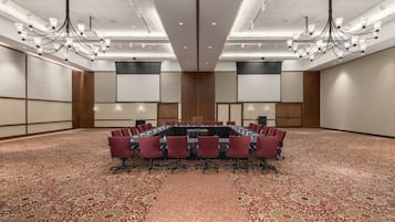 A conference room with a long table, red chairs, and a patterned carpet.