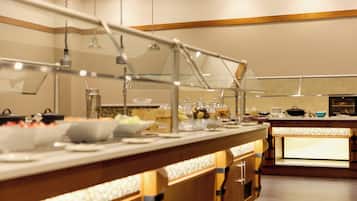 A buffet setup with a variety of food items and a counter with a glass display case.