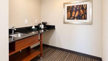 Baño de hotel con lavamanos, espejo y cafetera.
