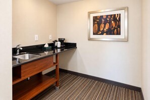 Baño de hotel con lavamanos, espejo y cafetera.