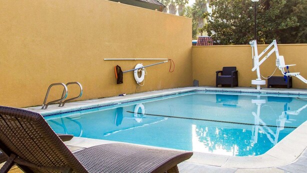 Una piscina con sillas de descanso, un flotador salvavidas y una escalera.