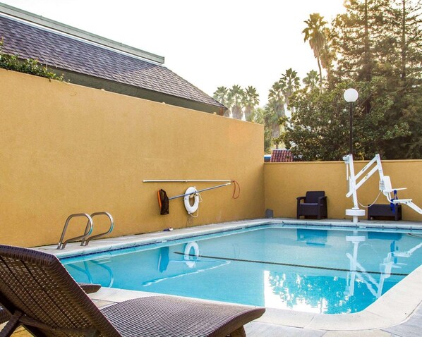 A swimming pool with lounge chairs, a lifebuoy, and a pool ladder. - Rodeway Inn (Martinez)