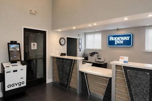 A reception area with a clock, a digital display, and a sign for Rodeway Inn.