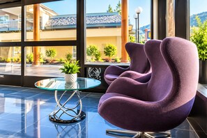 A modern lobby with a glass table, purple chairs, and a view of the building's exterior.
