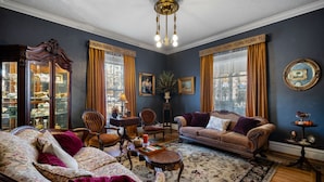 Un salon traditionnel avec un canapé, des fauteuils, une table basse et un lustre.