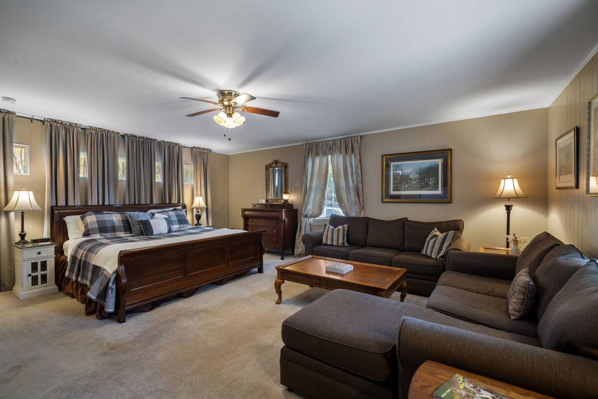 A well-furnished bedroom with a large bed, a sofa, a coffee table, and a ceiling fan.