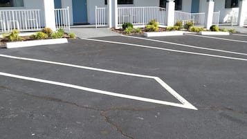 A motel with a central entrance, a covered parking area, and a row of rooms with a blue door.