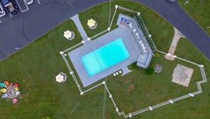 An aerial view of a swimming pool area with a fenced deck, lounge chairs, and a small pavilion. - Carolina Motel (Franklin)