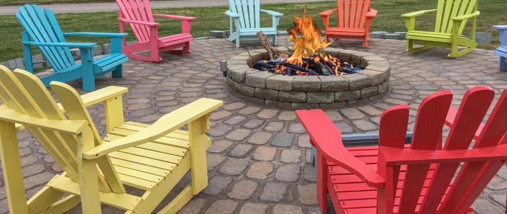 A fire pit surrounded by colorful Adirondack chairs.