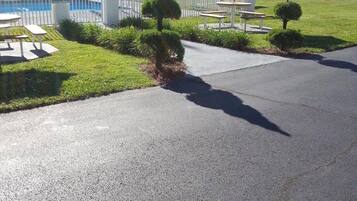 A motel with a fenced pool area, a small garden with trimmed bushes, and a picnic table.