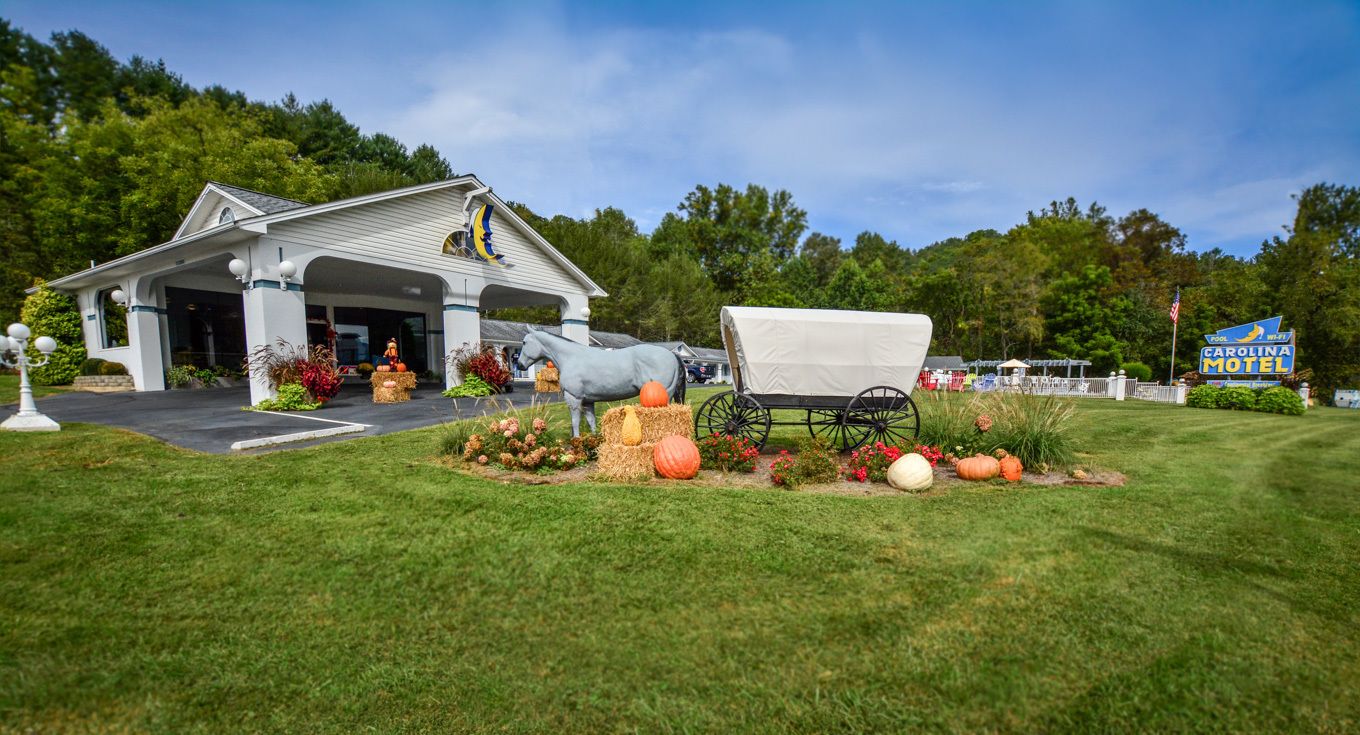 A white building with a porch, a covered wagon, and a sign for Carolina Motel.