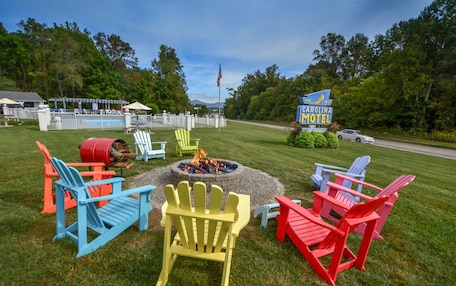 A Carolina Motel sign, outdoor seating with Adirondack chairs, a fire pit, and a pool area.