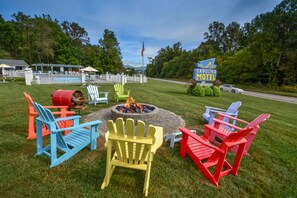 A Carolina Motel sign, outdoor seating with Adirondack chairs, a fire pit, and a pool area. - Carolina Motel (Franklin)