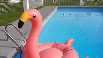 A swimming pool with a pink flamingo float.