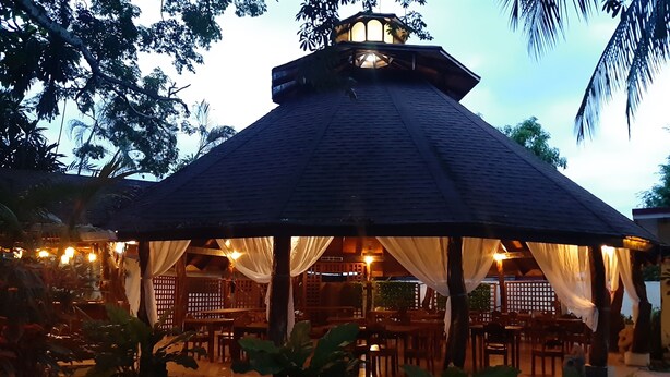 A gazebo-style outdoor seating area with tables and chairs, surrounded by greenery. - Hotel Samara Beach (Sámara)