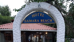 The entrance to Hotel Samara Beach with a red-tiled roof and a white, textured archway. - Hotel Samara Beach (Sámara)