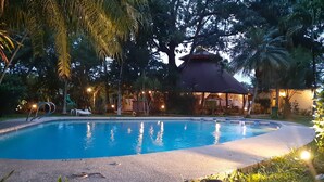 A swimming pool with a surrounding deck, a covered seating area, and palm trees. - Hotel Samara Beach (Sámara)