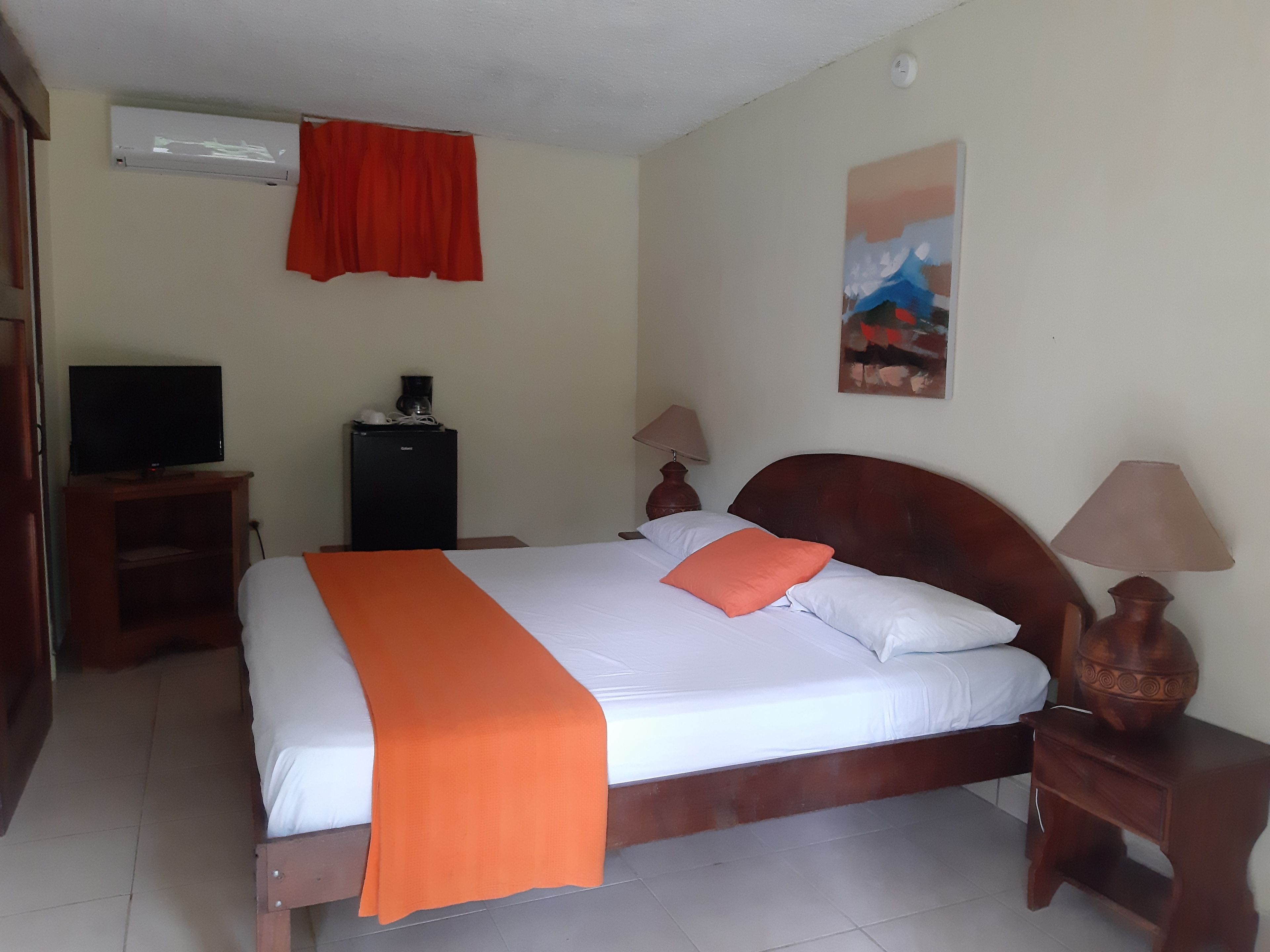 A hotel room with a bed, a television, a desk, and a small cabinet.