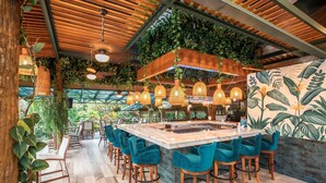 A bar area with a central island, bar stools, hanging lights, and a tropical mural. - Hotel Los Lagos Spa & Resort (La Fortuna)