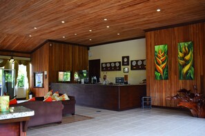 A reception area with a wooden ceiling, a reception desk, a couch, and two paintings on the wall.