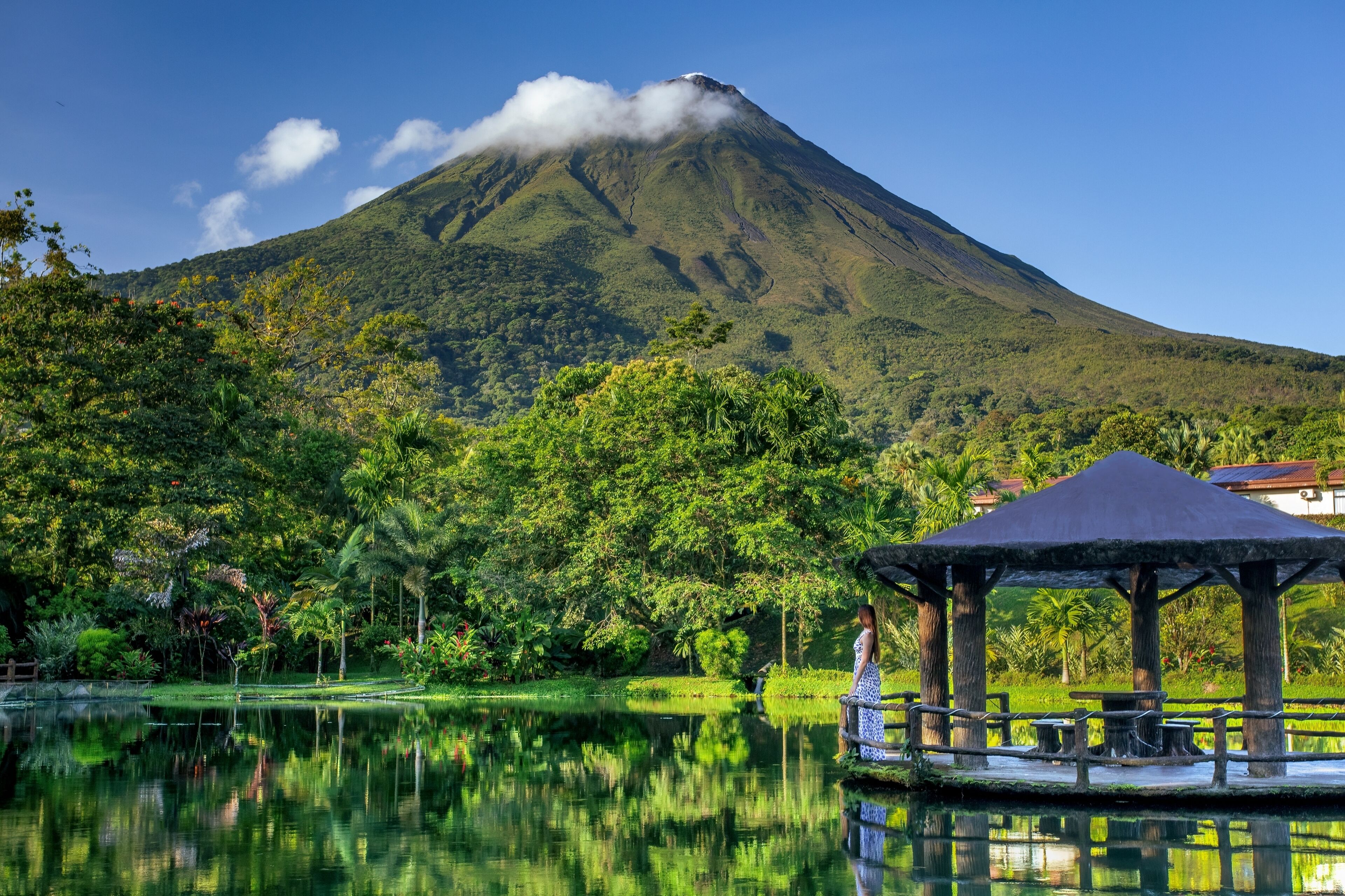 A serene landscape with a mountain, a reflective pond, and a gazebo.