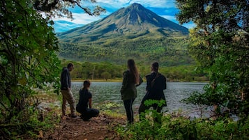Un grupo de personas junto a un lago, con una montaña al fondo.