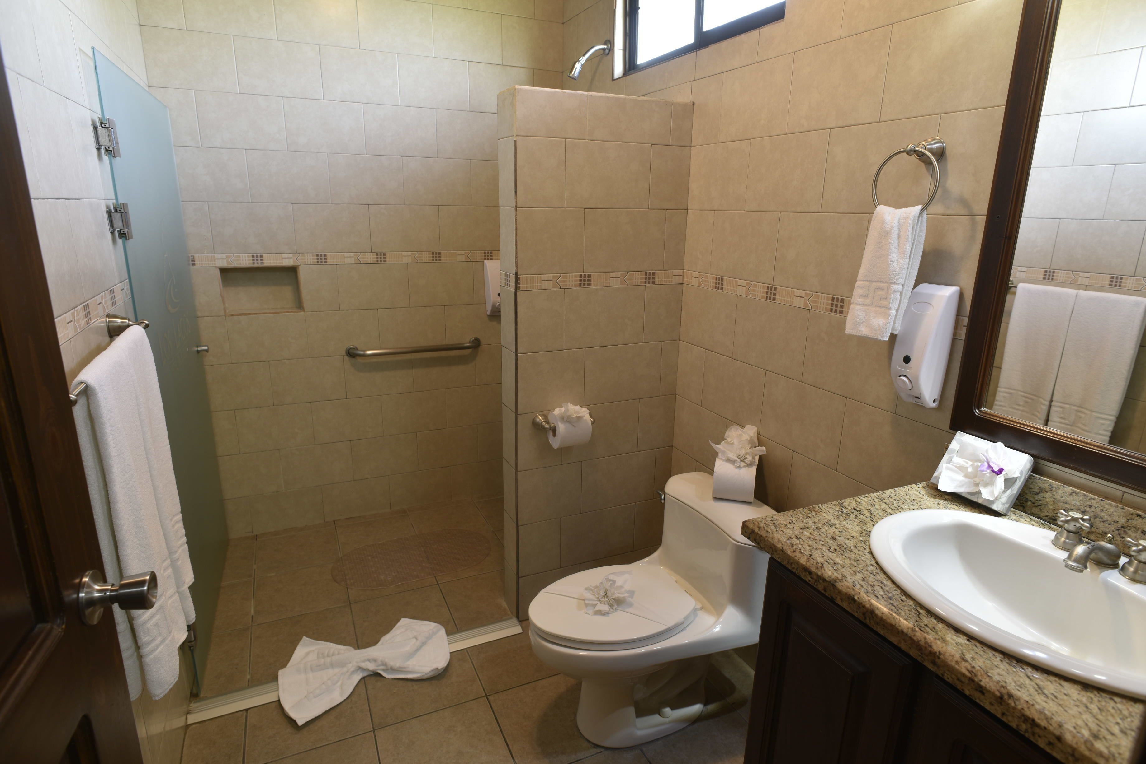 Ein Badezimmer mit Dusche, Toilette, Waschbecken und Handtuchhalter.