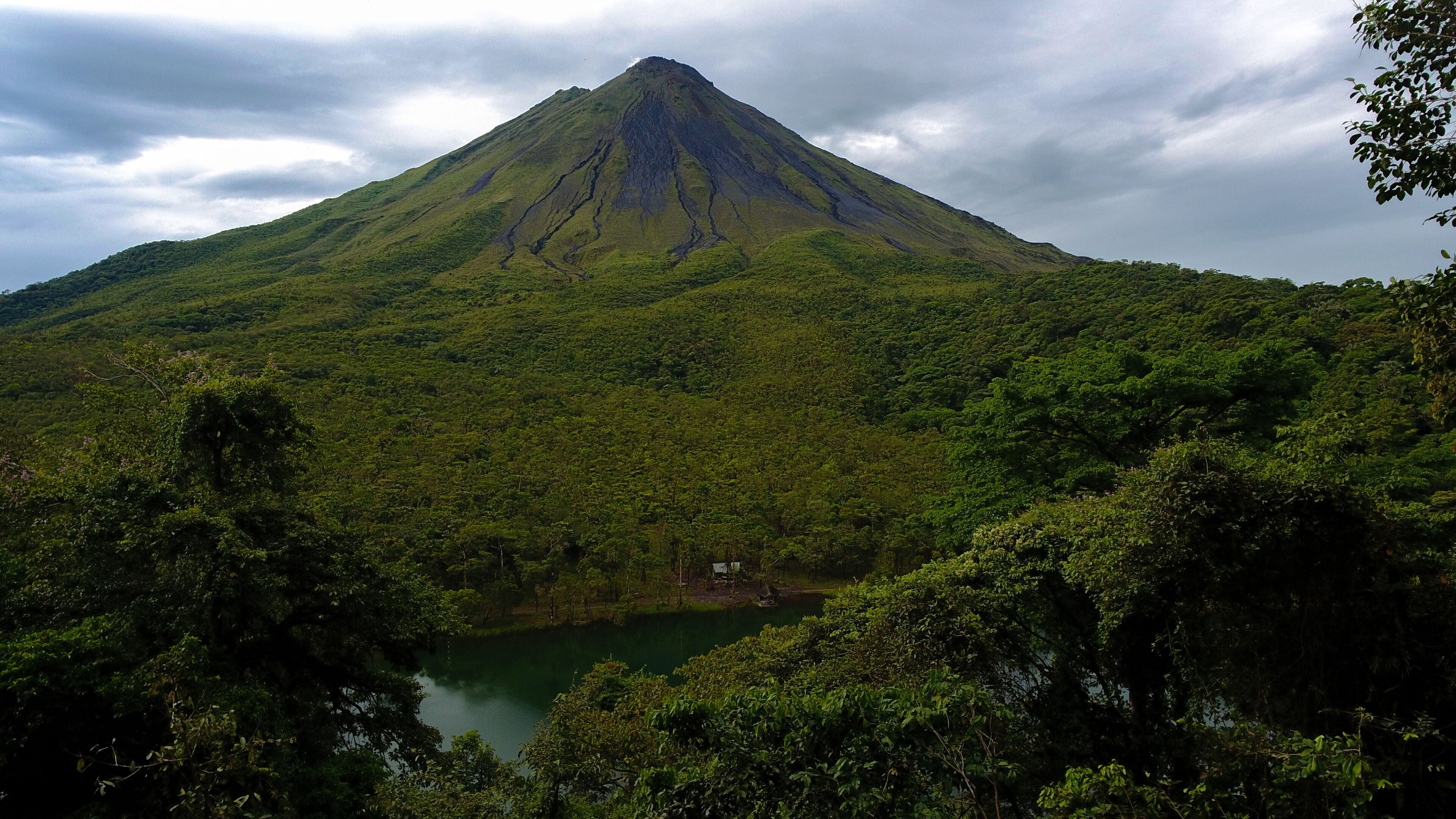 A mountain with a lake at its base, surrounded by dense greenery.