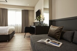 Quarto de hotel moderno com uma cama grande, uma escrivaninha e vista para a cidade.