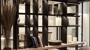 Un interior moderno con una estantería que muestra varios objetos decorativos y libros.