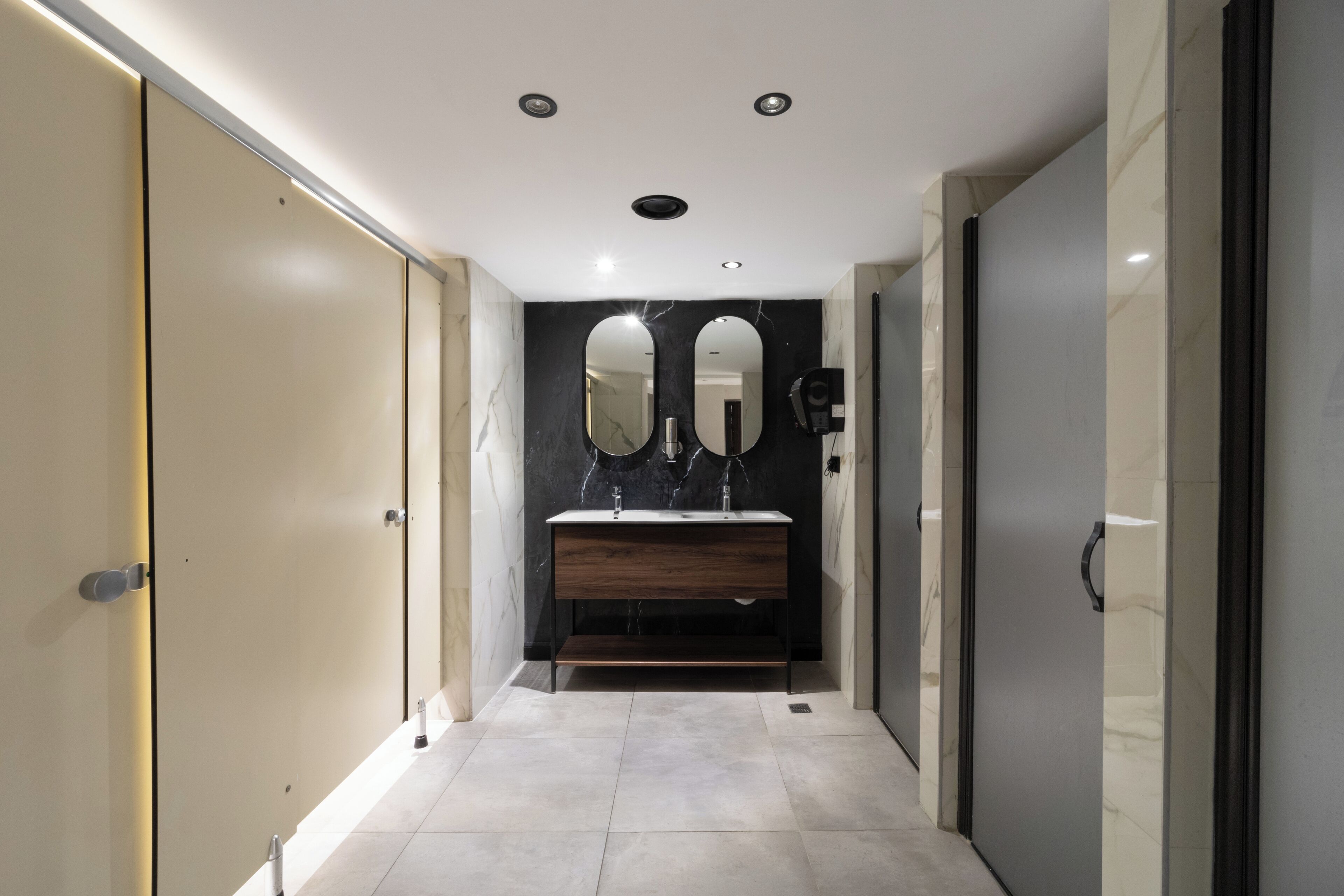 A modern bathroom with a marble vanity, two mirrors, and recessed ceiling lights.