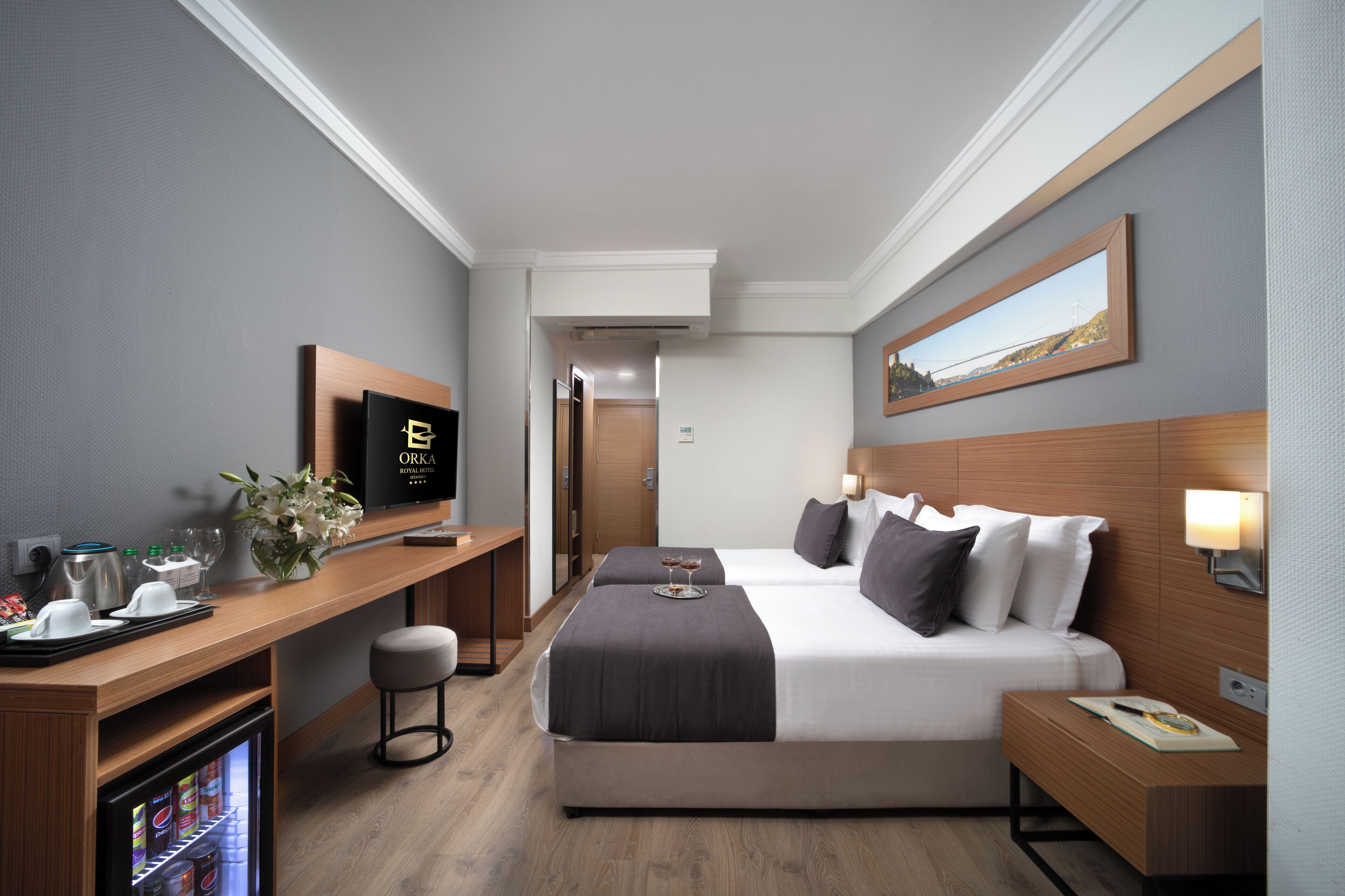 Une chambre d’hôtel équipée d’un lit, d’une table de chevet, d’une télévision, d’un bureau et d’un réfrigérateur.