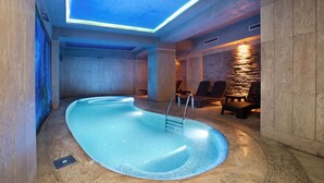 An indoor swimming pool with a modern design, a stone wall, and a seating area with chairs. - Orka Royal Hotel & Spa (Istanbul)