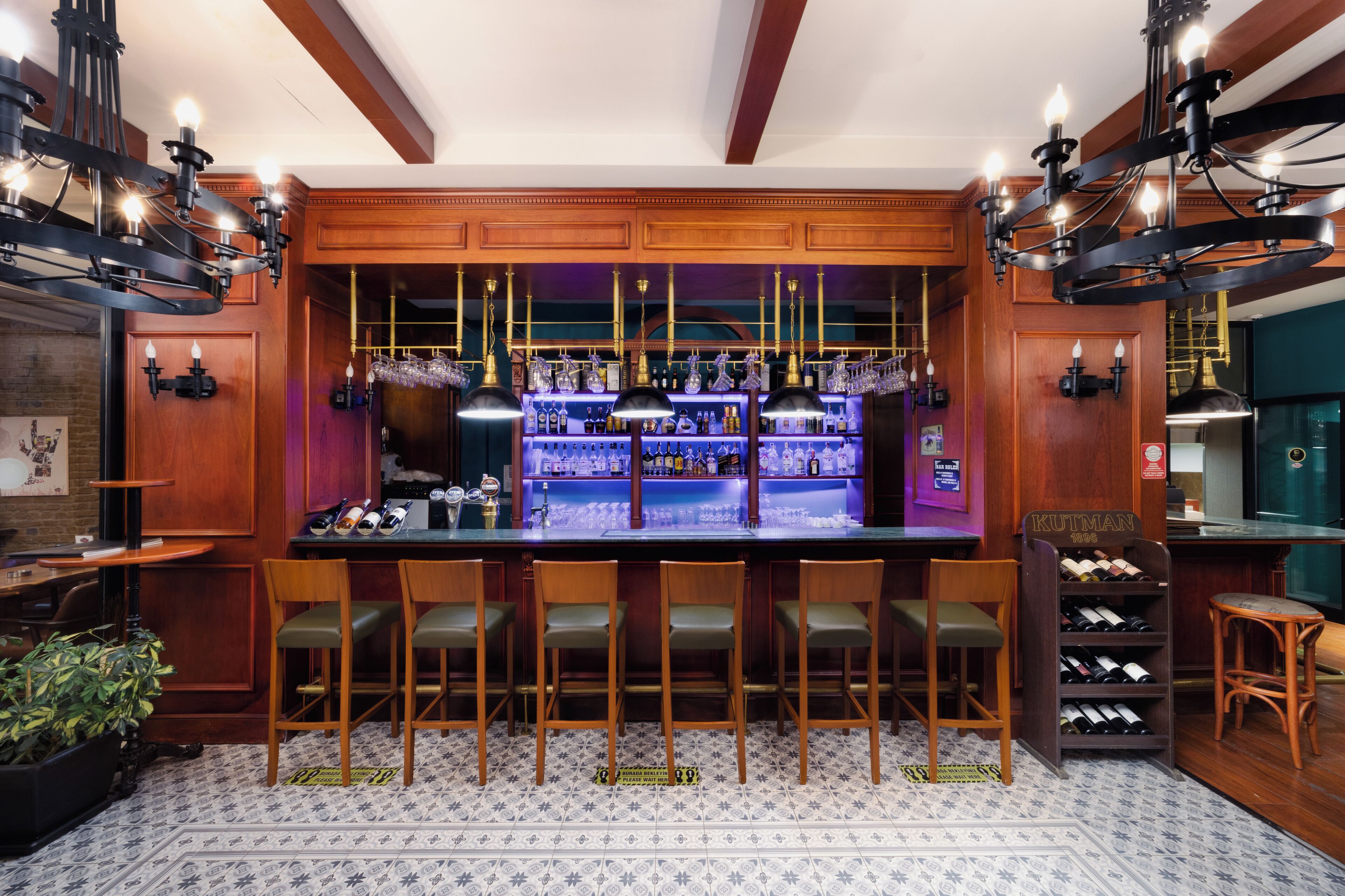 A bar area with wooden bar counters, bar stools, and a wine rack.