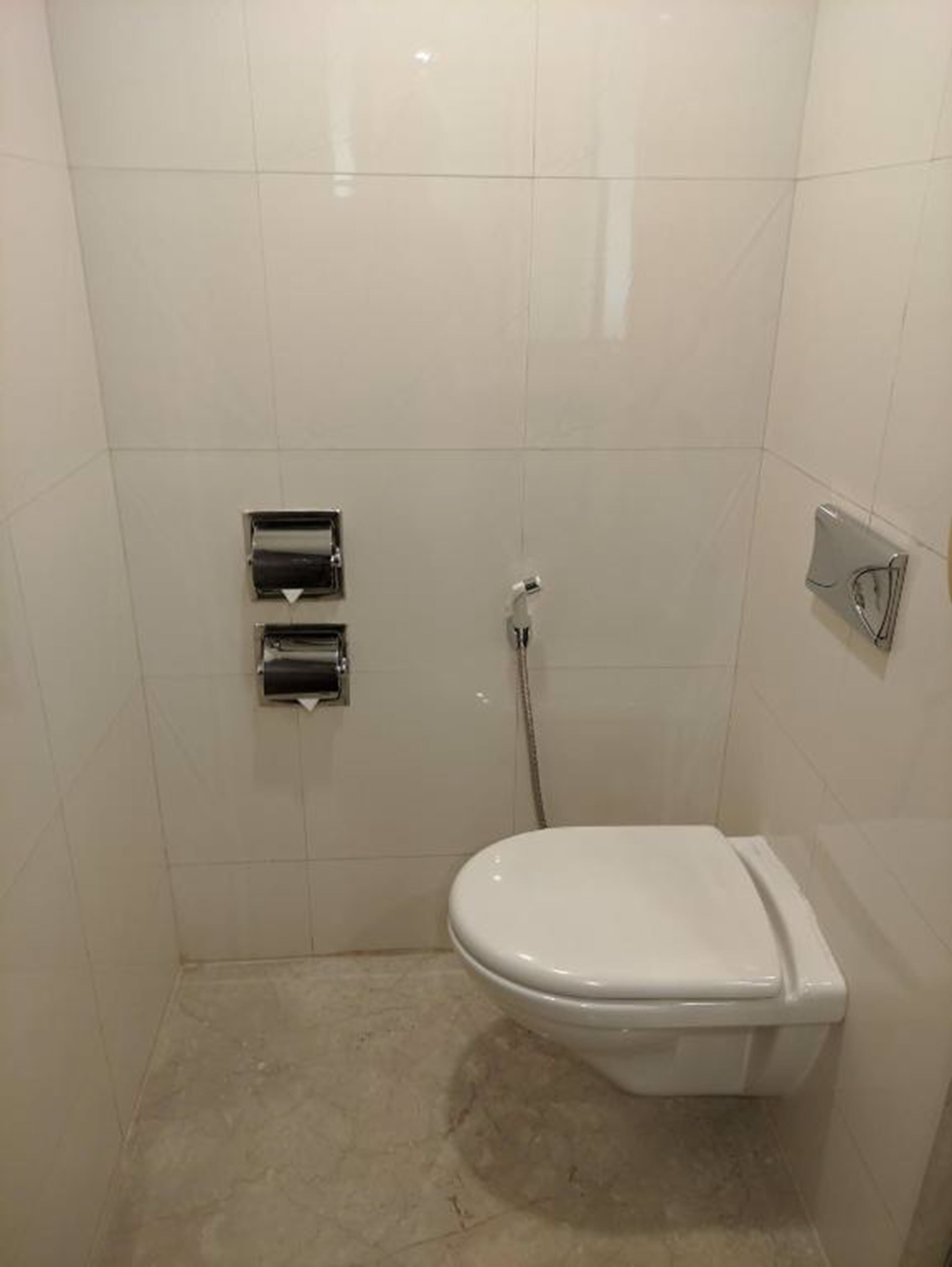 A small, clean bathroom with a toilet, a hand dryer, and a paper towel dispenser.