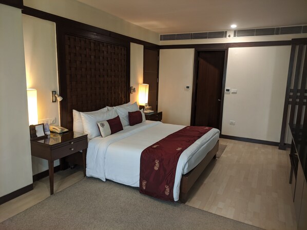 Habitación de hotel con una cama grande, dos mesitas de noche, un cabecero de madera, un corredor de cama rojo y suelo alfombrado.