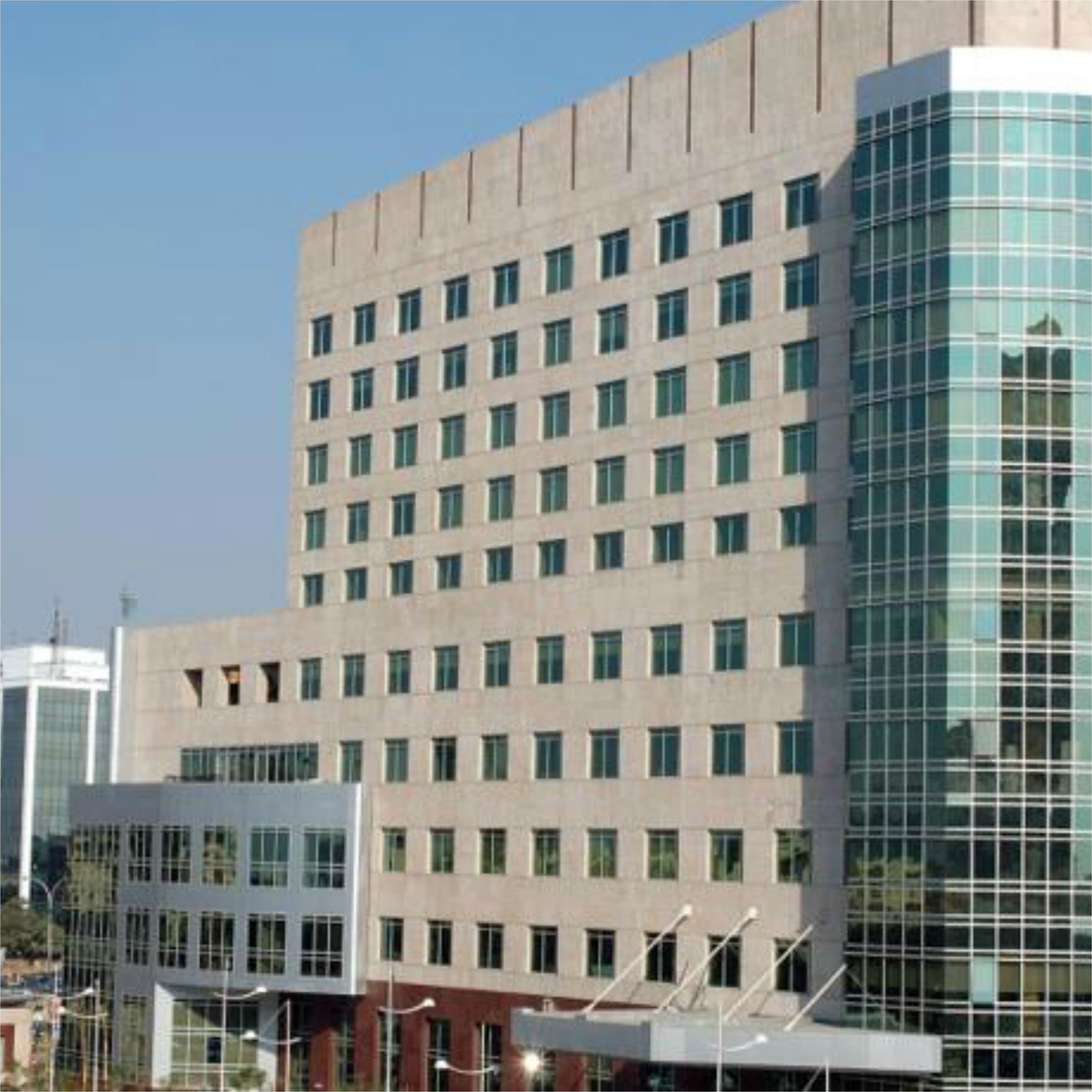 A multi-story building with a grid of windows and a glass facade on one side.