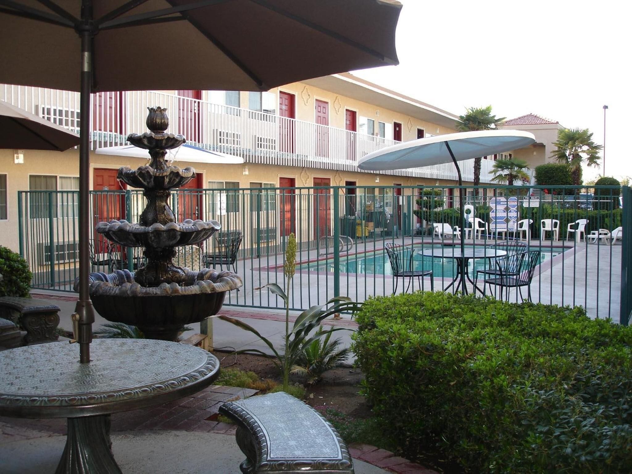 Un patio con una fuente, piscina y zona de estar al aire libre.