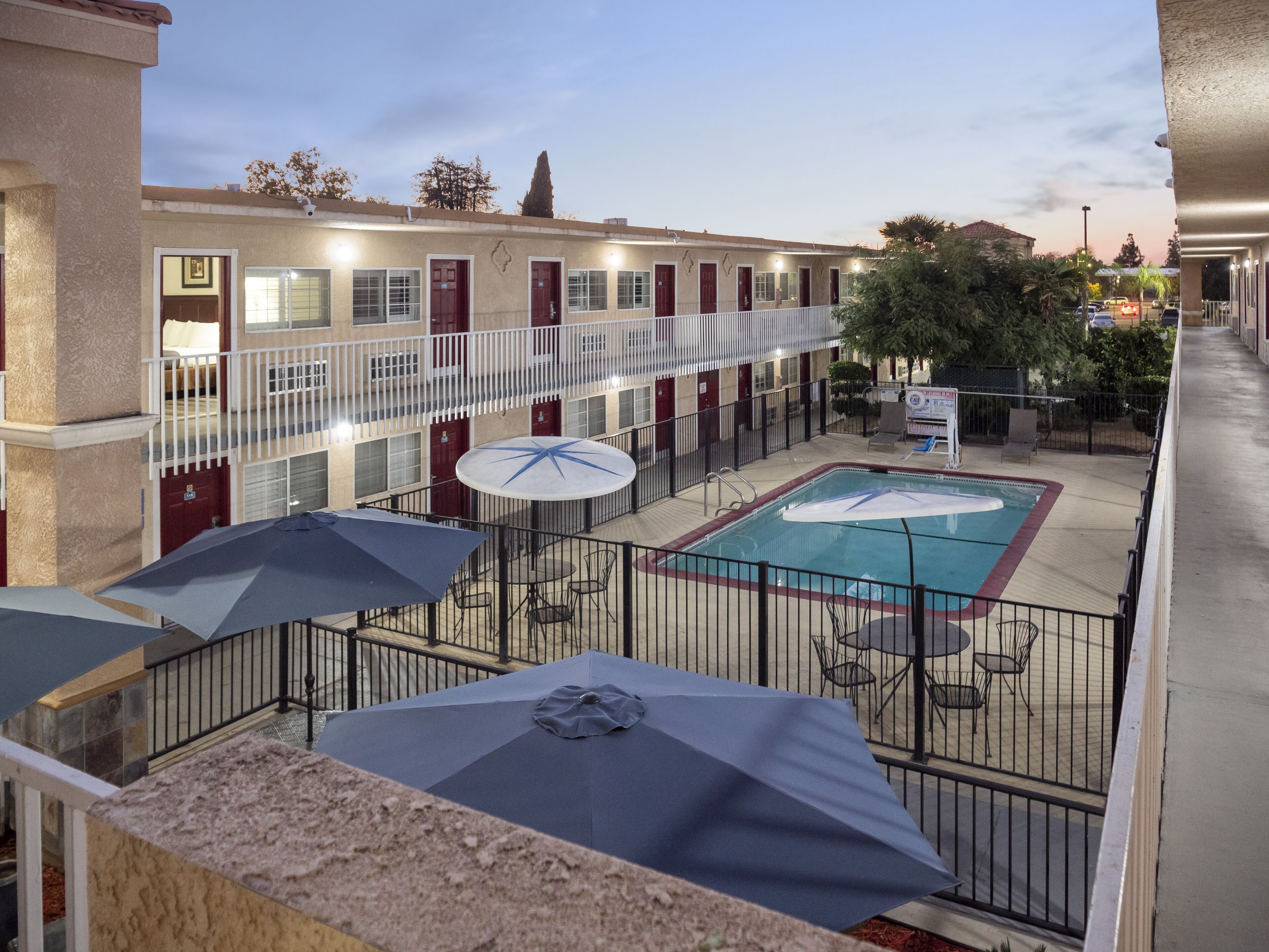 A hotel courtyard with a swimming pool, outdoor seating, and a covered area with umbrellas.