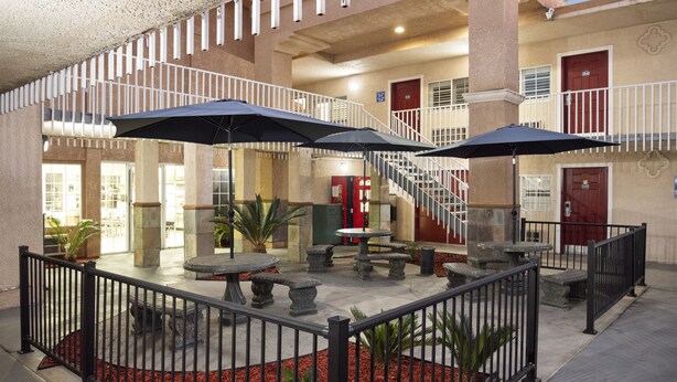 A courtyard with outdoor seating, a staircase, and a covered area with umbrellas. - Dream Inn (Fresno)