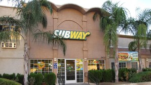 A Subway restaurant with a clear entrance, parking lot sign, and a promotional sign for avocado season. - Dream Inn (Fresno)