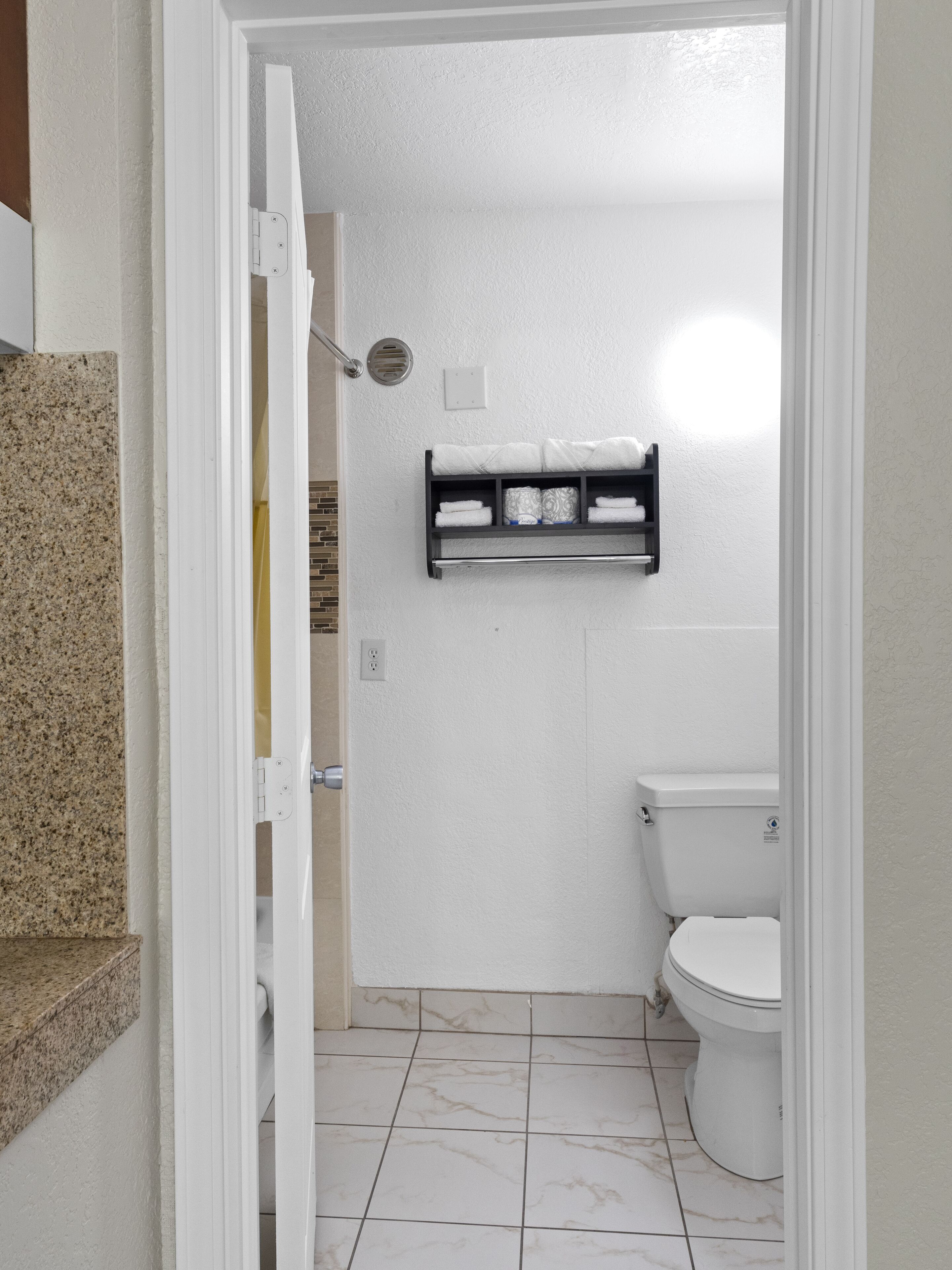 A bathroom with a toilet, a towel rack, and a shower area.