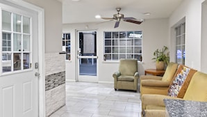 A spacious room with a white door, a ceiling fan, a large window with a Subway sign, and a seating area with a table and chairs. - Dream Inn (Fresno)