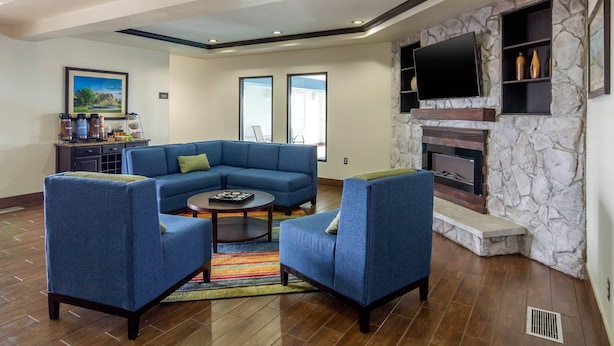 A living room with a sectional sofa, two armchairs, a coffee table, a fireplace, a flat-screen TV, and a stone accent wall. - Comfort Inn & Suites Sterling (Sterling)